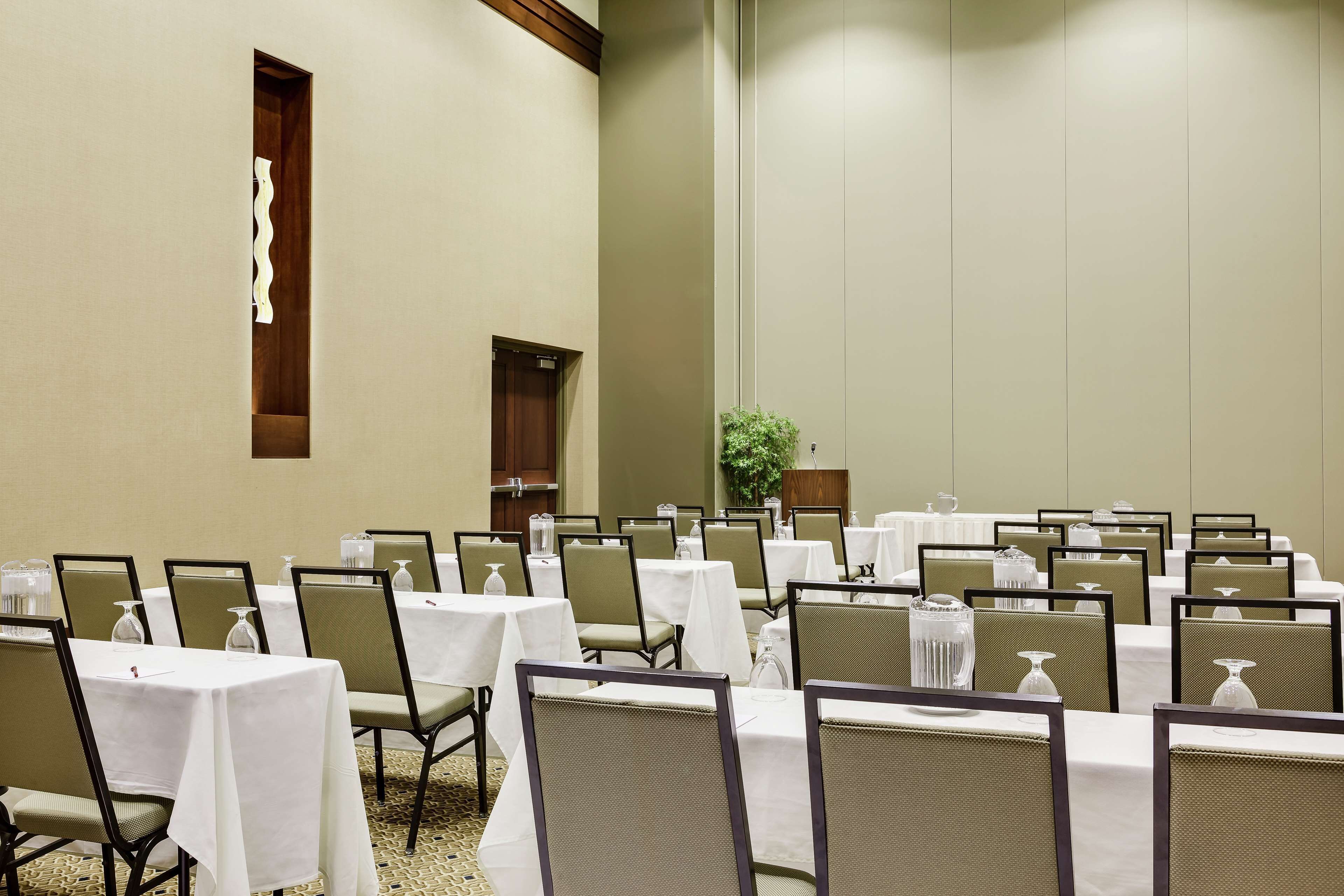 A conference room with tables and chairs, a wooden door, and a plant.