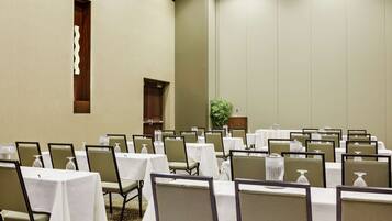 A conference room with tables and chairs, a wooden door, and a plant.
