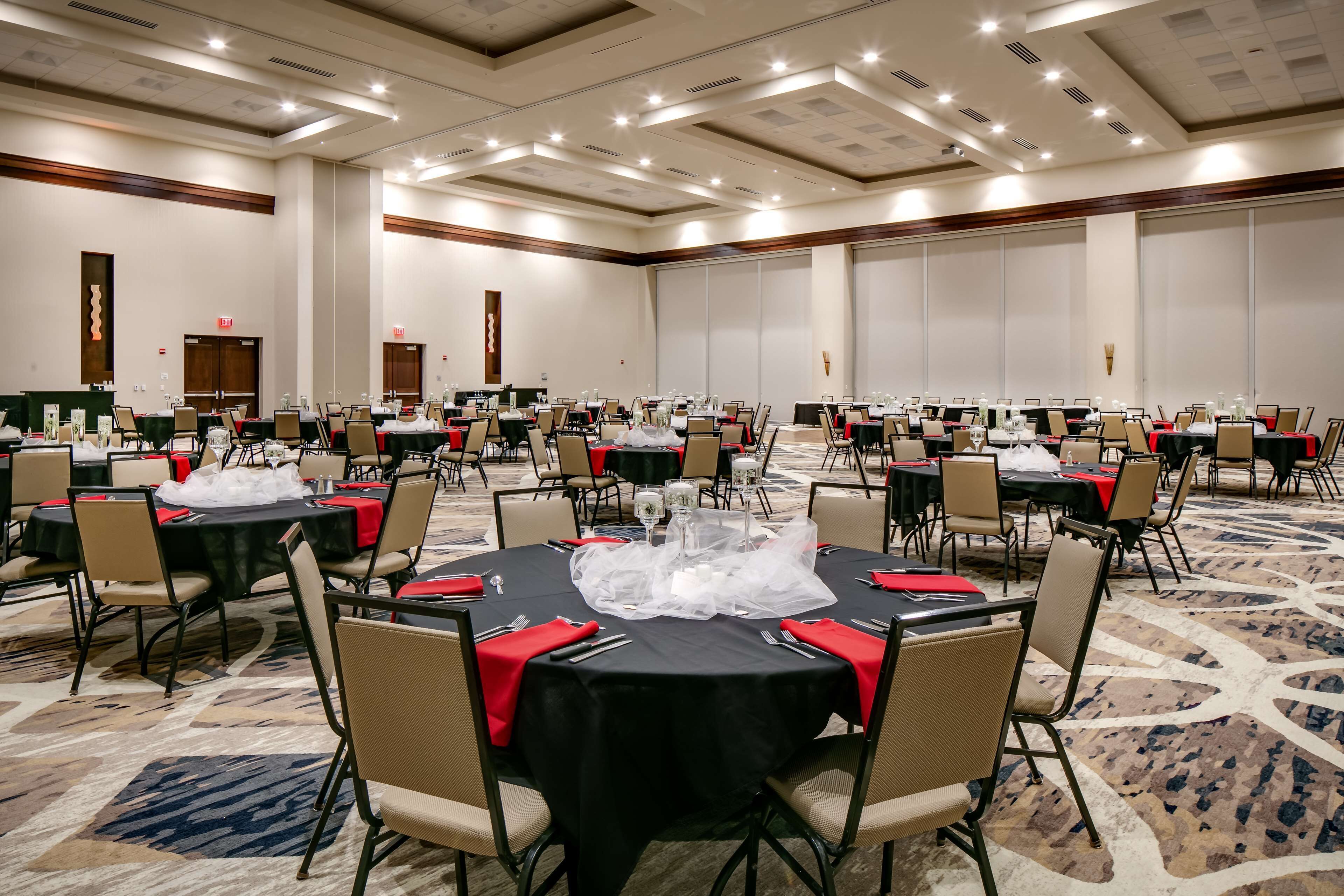 A conference room with multiple tables, chairs, and a carpeted floor.