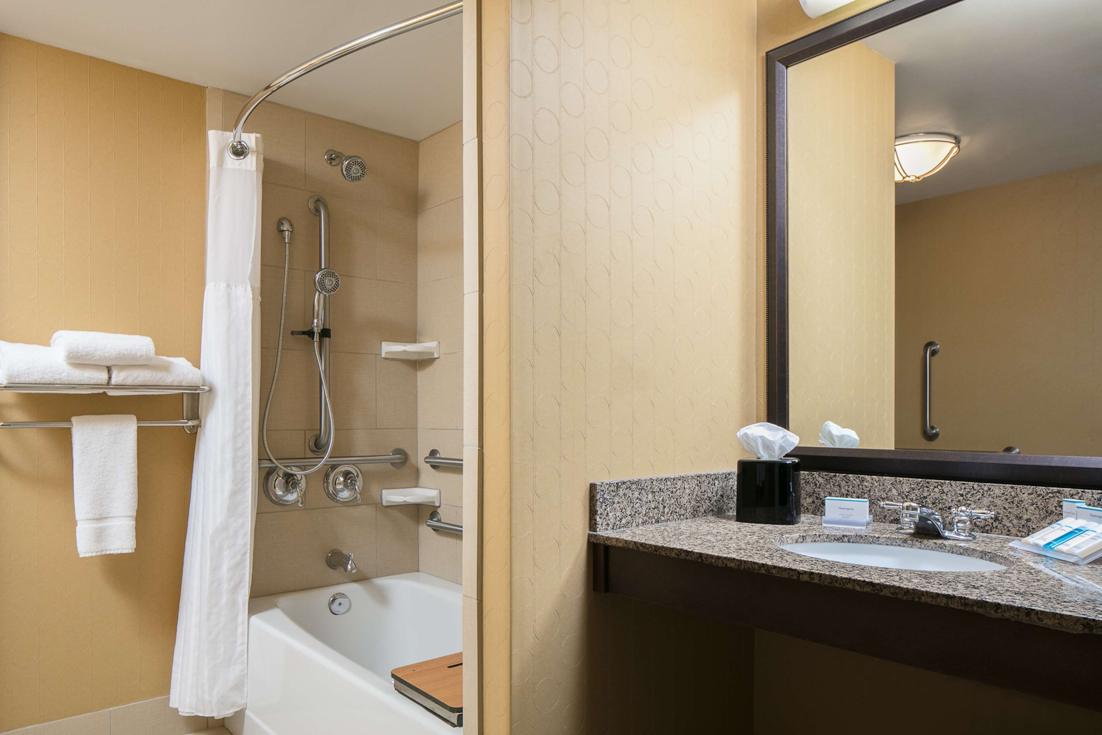 Un baño de hotel con bañera, ducha y lavabo con espejo.