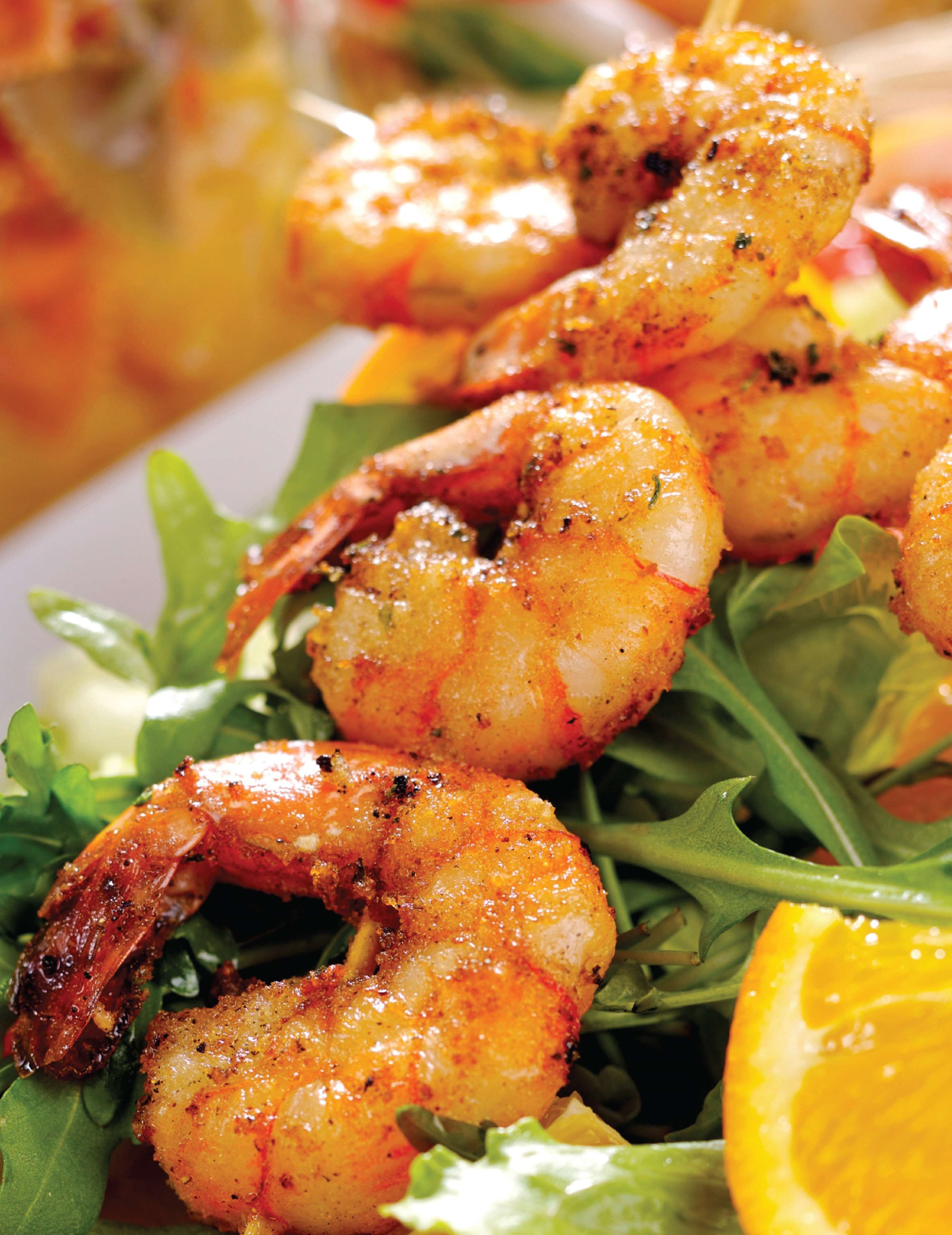 A plate of cooked shrimp served on a bed of greens.