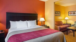 Une chambre d’hôtel avec un grand lit, deux tables de chevet, une chaise et un bureau.