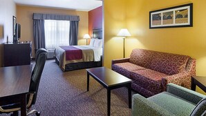Une chambre d’hôtel avec un lit, un bureau, un canapé et une chaise. Il y a une télévision sur le bureau, une lampe sur le bureau et un tableau au mur.