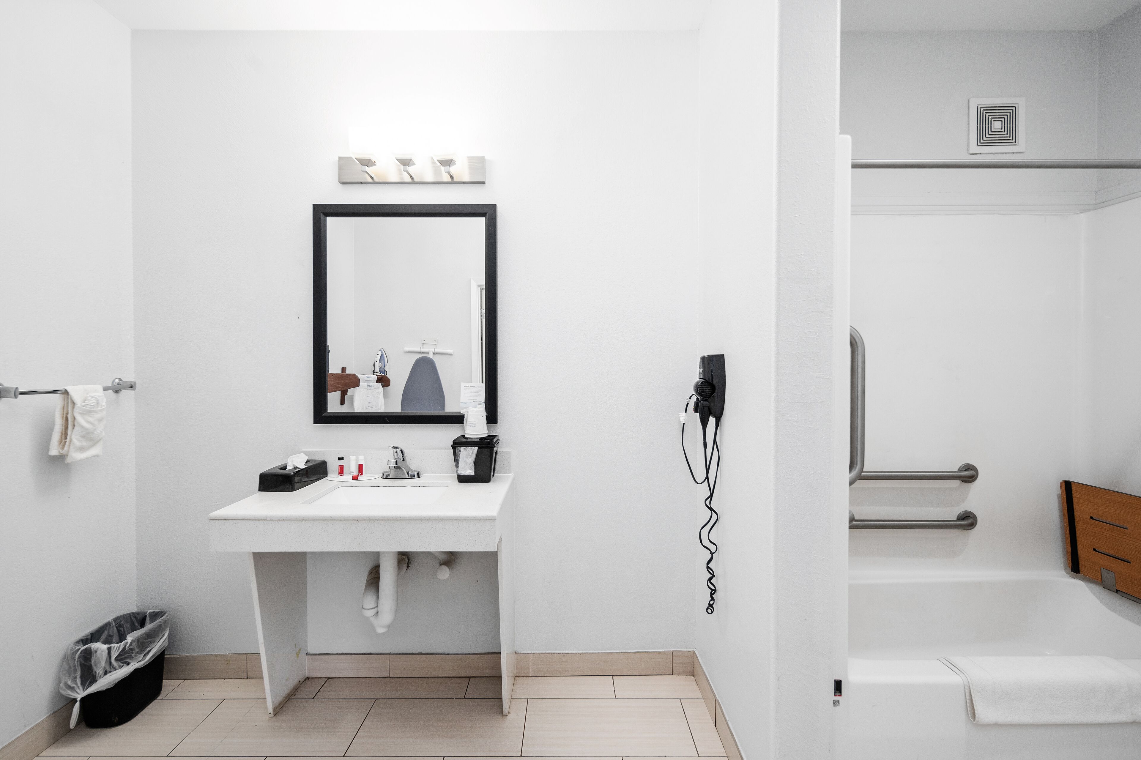 Un baño moderno con lavamanos, espejo y toallero blancos.