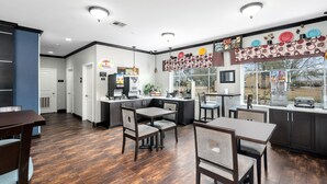 A modern kitchen with dark wood flooring, a central island, and a window overlooking a yard. - Super 8 by Wyndham Mansfield LA (Mansfield)