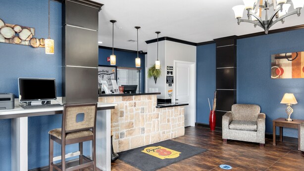 A modern hotel lobby with a reception desk, a seating area, and a bar. - Super 8 by Wyndham Mansfield LA (Mansfield)