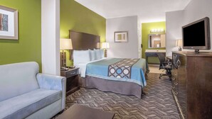 A hotel room with a bed, a desk, a chair, a television, and a couch. - Super 8 by Wyndham Mansfield LA (Mansfield)