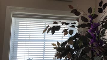 Een bord met de tekst ‘uitgang’ boven een raam met zonwering en een bloempot.