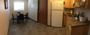 A compact kitchen with a refrigerator, sink, and basic appliances. - Budget Lodge (Saskatoon)