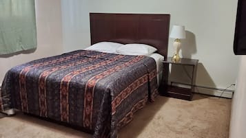 A bed with a patterned bedspread, a bedside table with a lamp, and a wall-mounted TV.