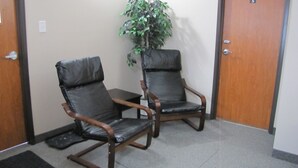 Two leather chairs with wooden frames in a hallway with a door marked '5' and a potted plant. - Budget Lodge (Saskatoon)