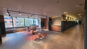 A modern interior with a reception desk, seating area, and large windows. - Novotel Bogotá Parque 93 (Bogotá)