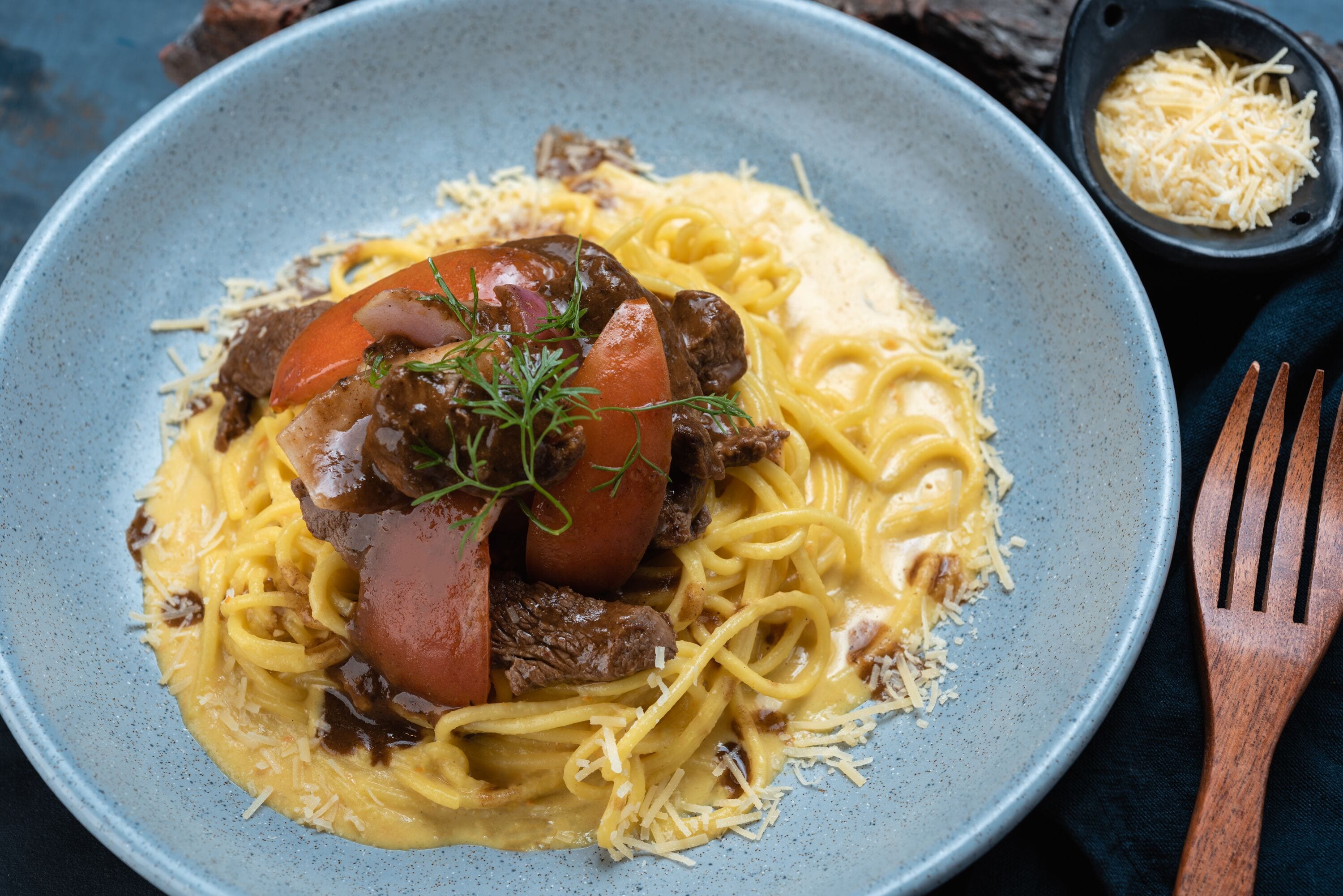 Une assiette de spaghettis à la viande et à la sauce tomate, garnie d’herbes.