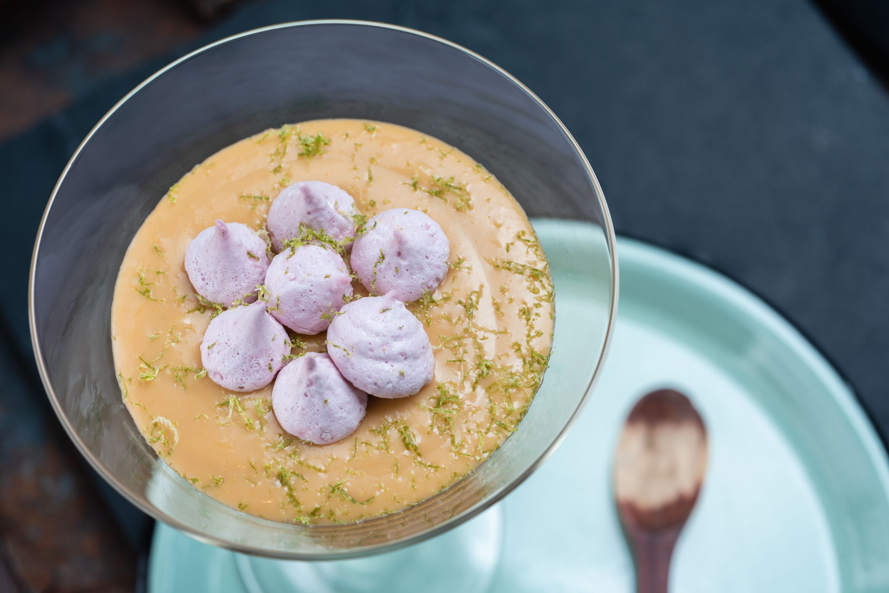 A dessert in a metal bowl with a spoon on a plate.