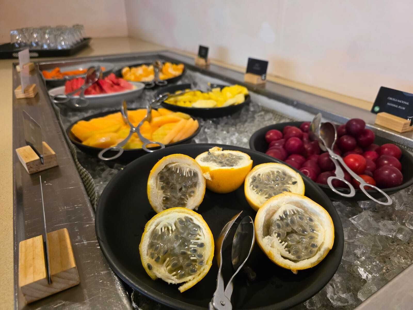 Ein Buffet mit verschiedenen Früchten, darunter Orangenscheiben, Marakuten und Pflaumen.