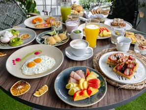 A breakfast buffet with various dishes, including eggs, fruits, pastries, and beverages.
