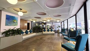 A modern lobby with a curved seating area, large windows, and a ceiling with circular light fixtures. - Novotel Bogotá Parque 93 (Bogotá)
