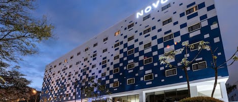 A Novotel hotel with a modern design, featuring a checkered facade and multiple windows.