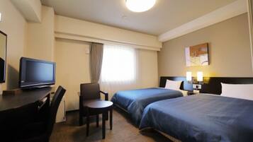 A hotel room with two beds, a desk with a television, a chair, and a nightstand with lamps.
