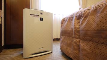 A room with a white air conditioner, a bed with a patterned cover, and a wooden door.