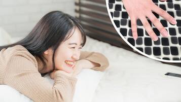 Una persona acostada en una cama con un almohadón y una manta.