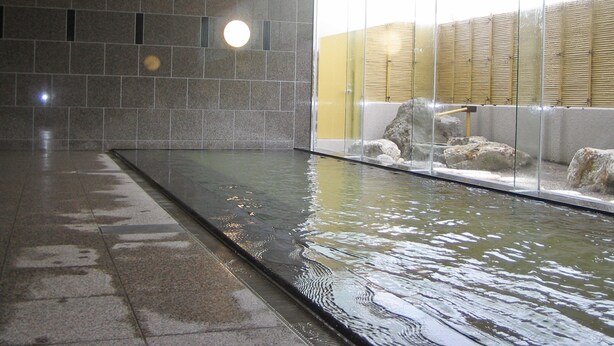 Ein großes Hallenbad mit klaren Glaswänden, einem gefliesten Boden und einer Holzzielung.