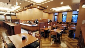 Ein geräumiges Restaurant mit Holztischen, einer zentralen Theke und großen Fenstern.