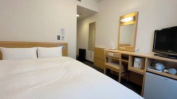Habitación de hotel con cama, escritorio con espejo, televisor y refrigerador pequeño.