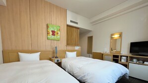Une chambre d’hôtel avec deux lits, une télévision, un bureau avec un miroir et un tableau au mur.