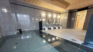 Une salle de bain moderne avec des carreaux de granit, une douche en verre et plusieurs lavabos équipés de sèche-mains.