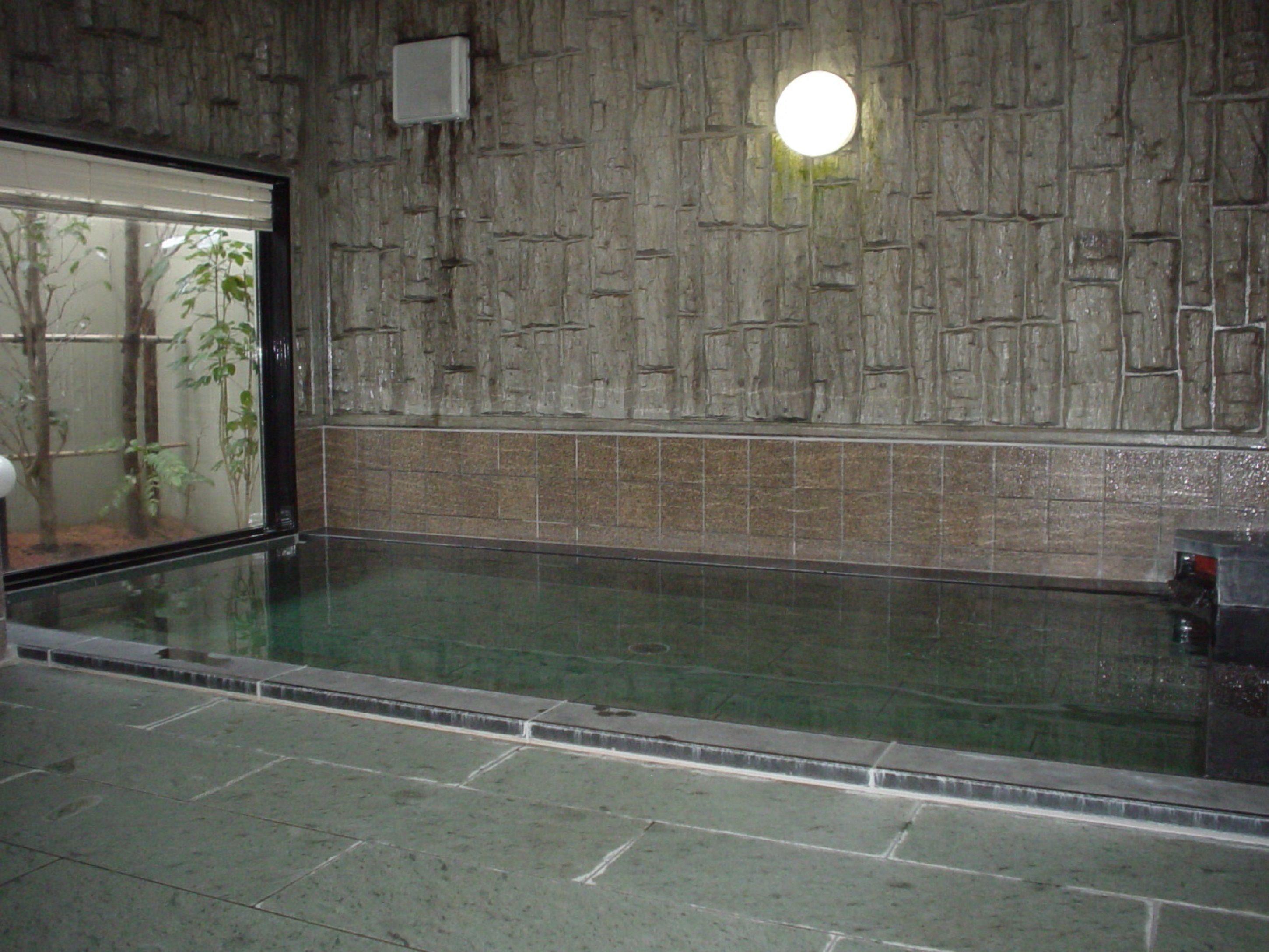 Ein Schwimmbad mit Steinmauer und Fenster.