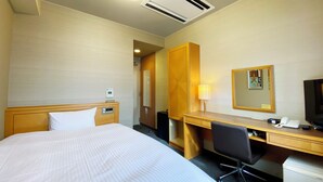 Una habitación de hotel con cama, escritorio, silla y televisor.