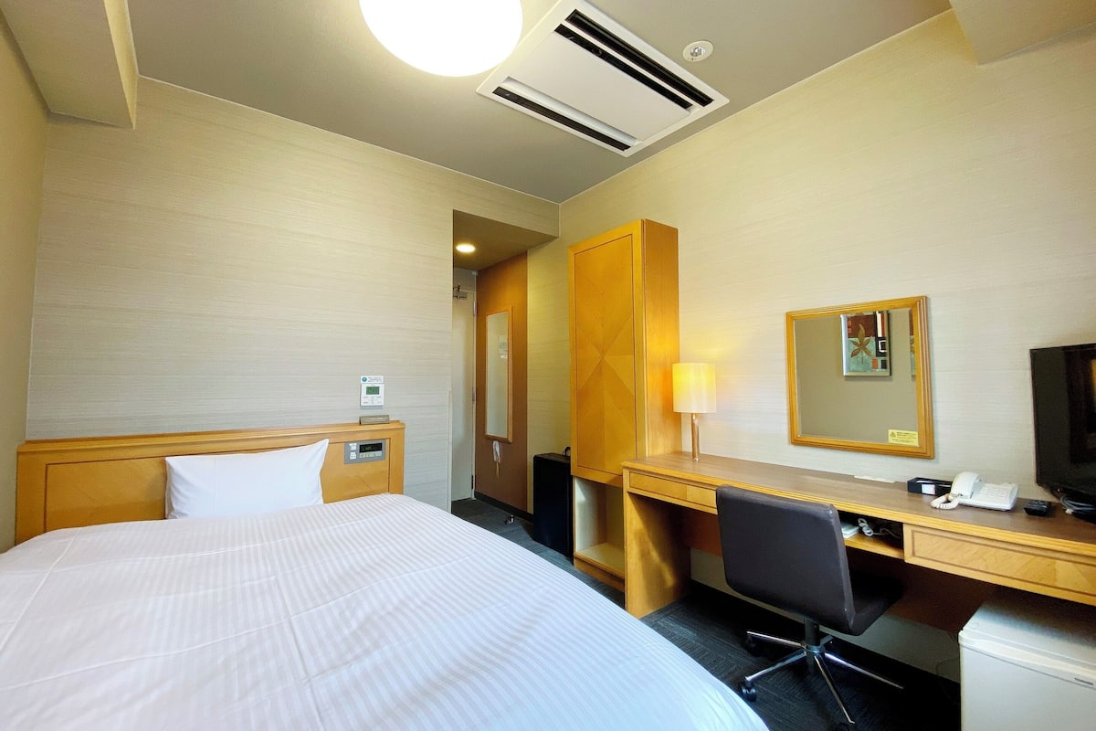Une chambre d’hôtel équipée d’un lit, d’un bureau, d’une chaise et d’un téléviseur.