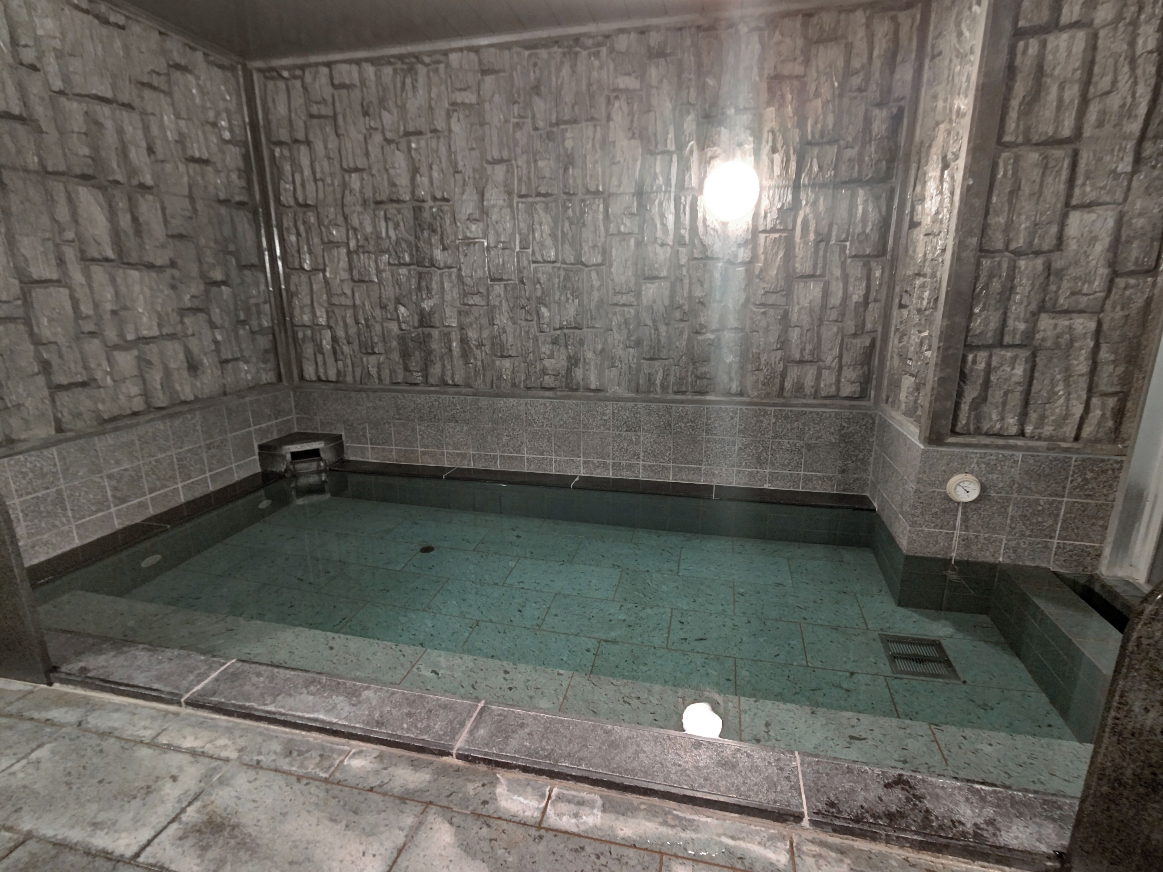 A small, rectangular pool with a stone wall surrounding it.