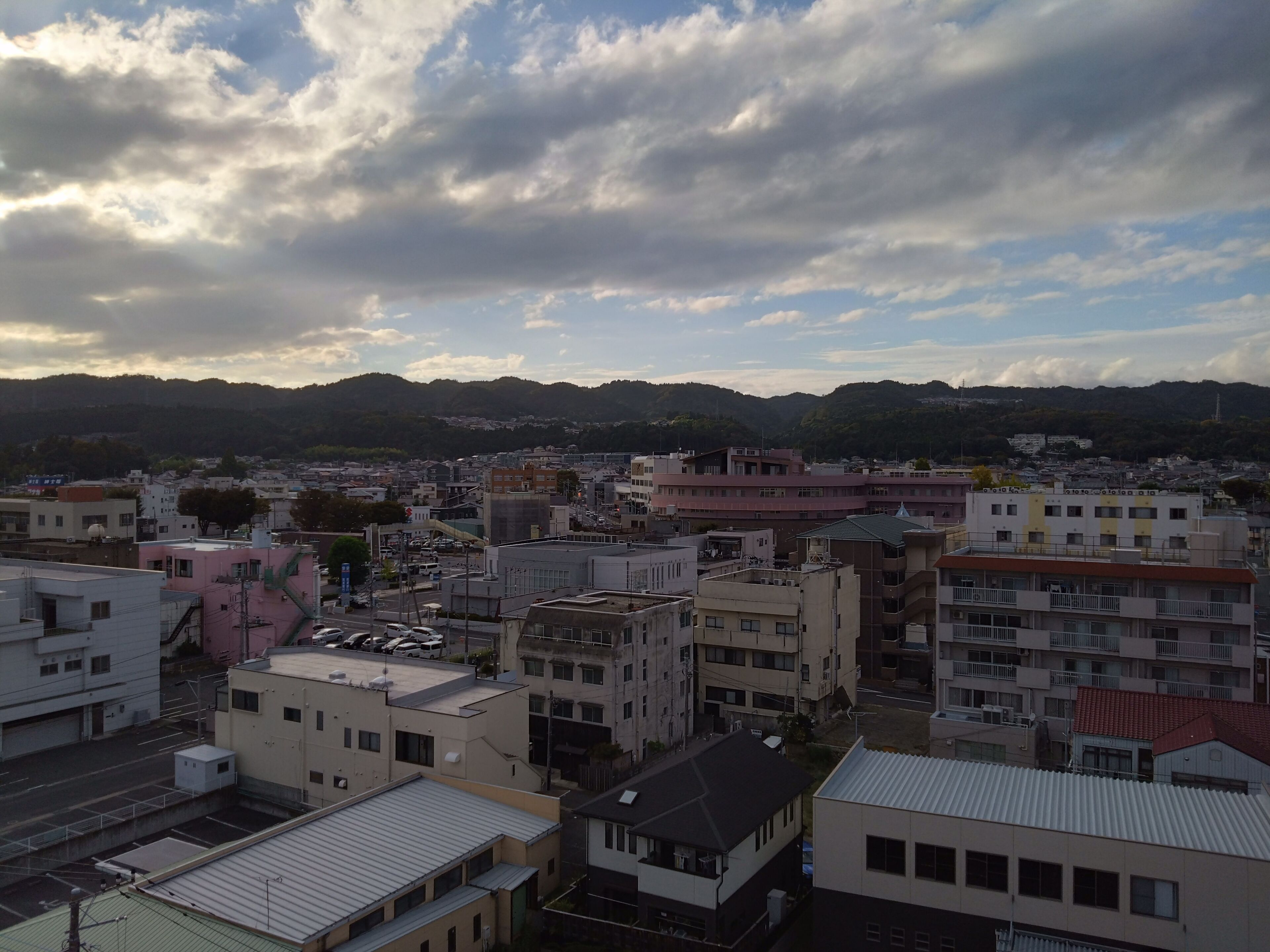Un paisaje urbano con edificios, calles y montañas al fondo.