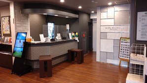 A hotel reception area with a digital information board, a reception desk, and a sign for Hotel Route Inn Hitachita. - Hotel Route Inn Hitachitaga (Hitachi)
