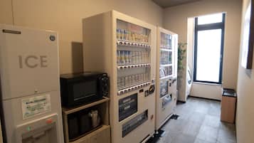 Zona de venta automática con dispensador de hielo, microondas y máquinas expendedoras de bebidas.