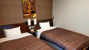 Habitación de hotel con dos camas, una mesita de noche, una lámpara de pared y una obra de arte con un árbol decorativo.
