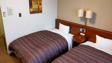A hotel room with two beds, a nightstand, a lamp, and a wall-mounted sign.