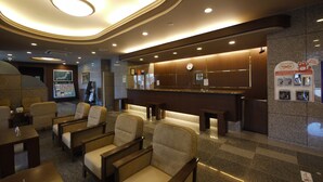 Vestíbulo de hotel con asientos, un mostrador de recepción y un reloj.
