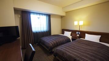 A hotel room with two beds, a TV, a desk, and a lamp.