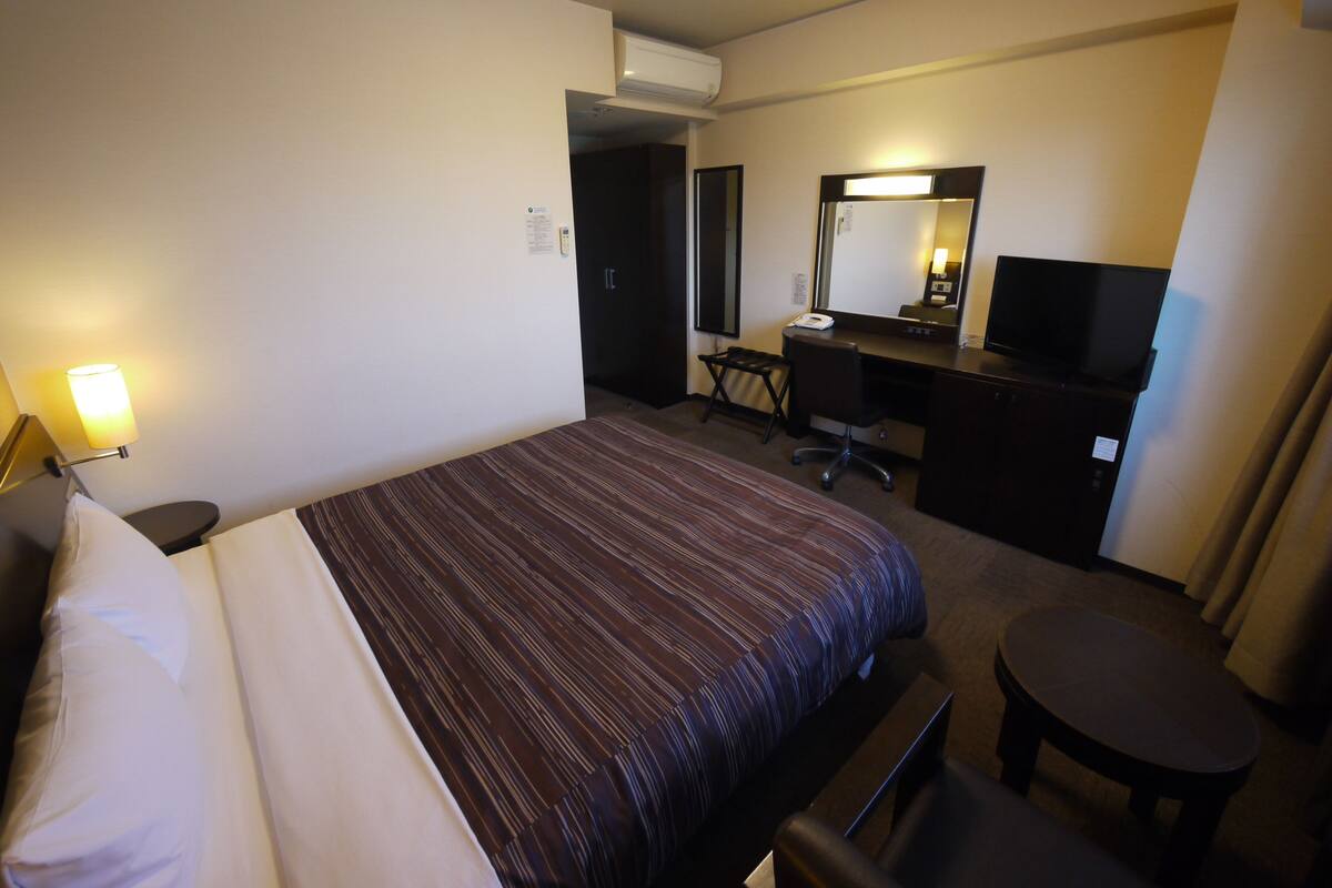 Una habitación de hotel con cama, escritorio, silla y una pequeña mesa.