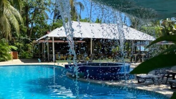 A clear blue pool with a hot tub, surrounded by palm trees and a covered area with tables and umbrellas. - Hotel Playa Westfalia (Matama)