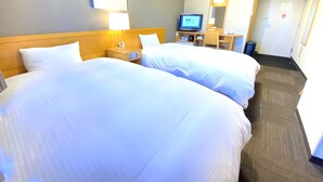 Habitació d'hotel amb dos llits, un escriptori amb un ordinador, un televisor i un mirall.