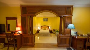 Habitación de hotel con cama, escritorio, silla, lámpara y televisor.