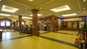 Un vestíbulo espacioso con una columna central, un mostrador de recepción y el letrero del Casino Golden Sea.