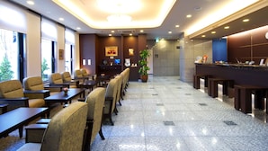 Un vestíbulo de hotel con mostrador de recepción, área de descanso y una gran planta en maceta.
