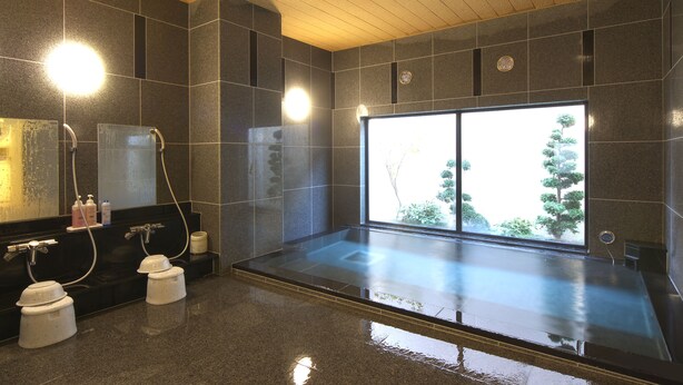 Un baño moderno con una bañera grande, un espejo y una ventana con vistas a árboles.