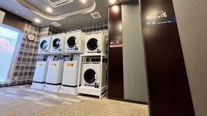 A men's public bath area with multiple washing machines and a clock on the wall. - Hotel Route Inn Mitsukaido Ekimae (Joso)
