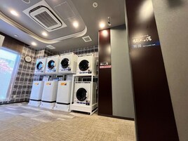 Zona de baños públicos para hombres con varias lavadoras y un reloj en la pared.